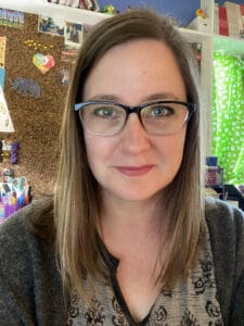 White woman in her mid-40s with glasses and shoulder length brown hair