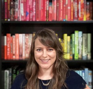 profile photo Photo of a white woman with light brown hair in front of a rainbow-sorted bookshelf